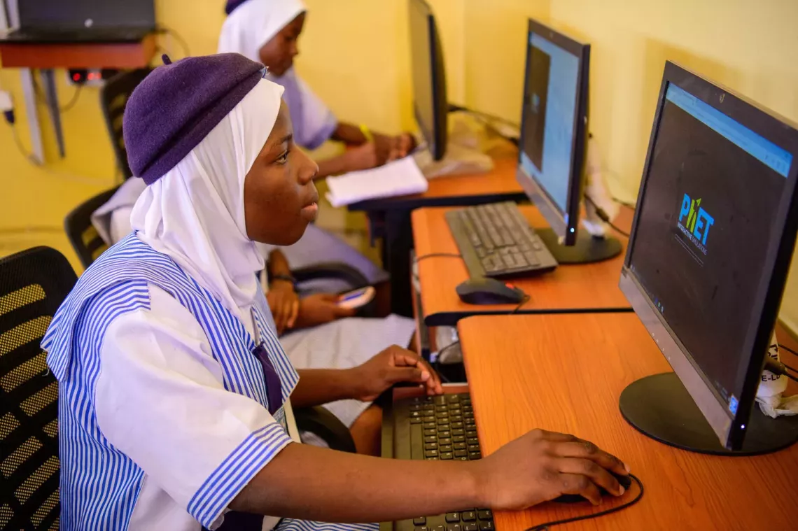 A teenage student in Nigeria works on a computer in a classroom