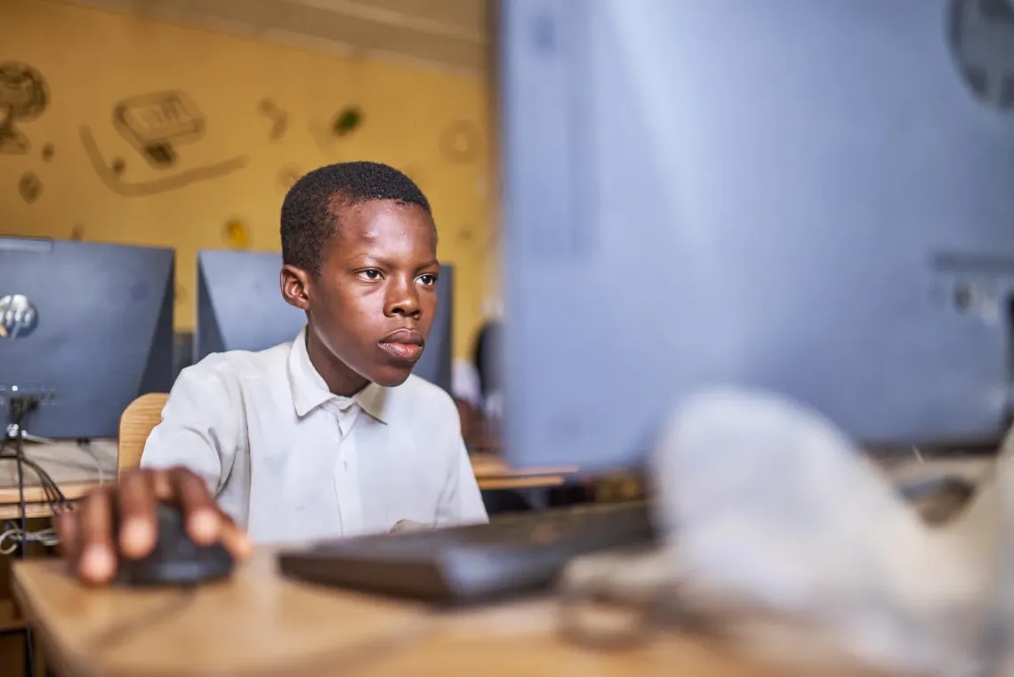 A young boy looks at his screen as he works on his computer