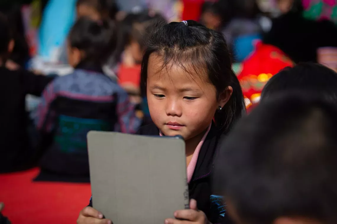 A young girl looking at the screen of an electronic tablet while at school