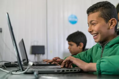 Child smiling looking at his laptop 