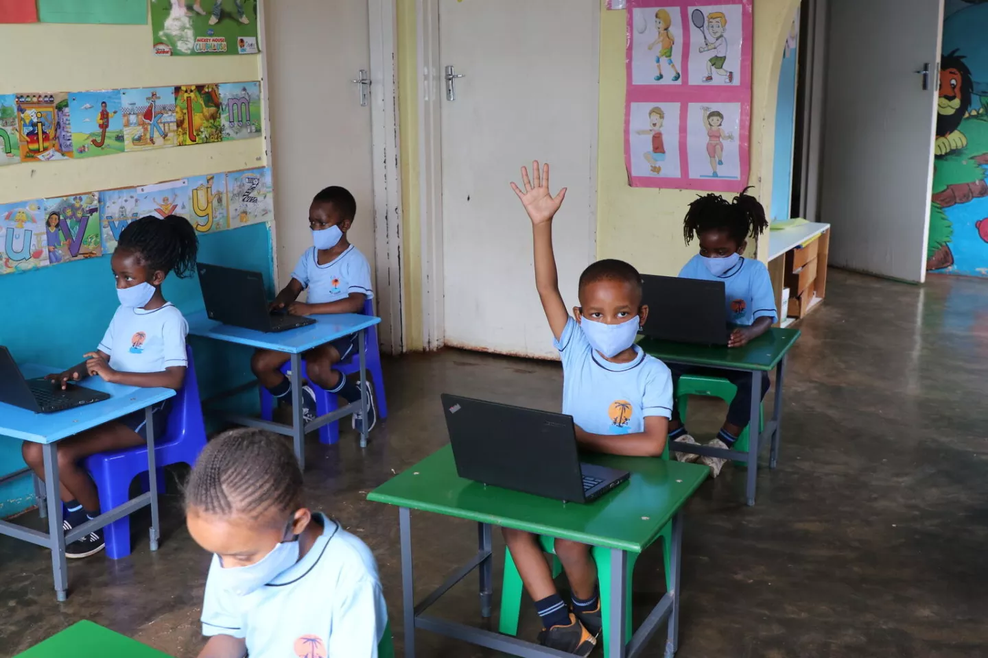 A boy raising his hand to participate in class in a classroom at Oasis Primary school in Hartcliffe, Harare, Zimbabwe
