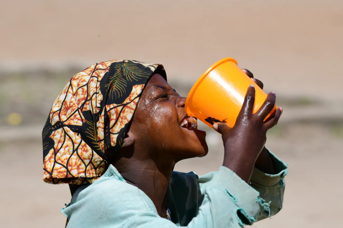 A girl drinking water at the playground of her school.