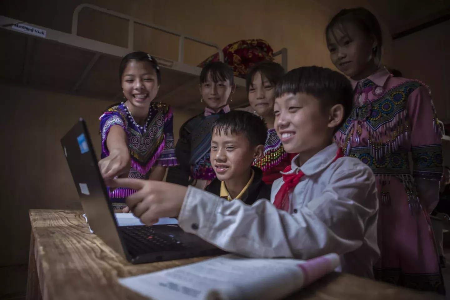 Children gather aroung and use computer