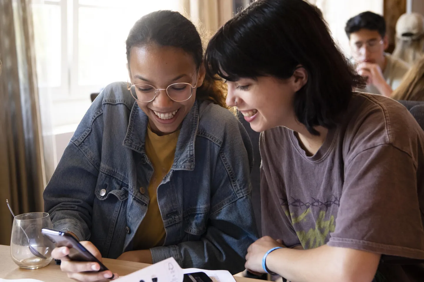 UNICEF youth volunteers laughing while looking at a mobile phone.