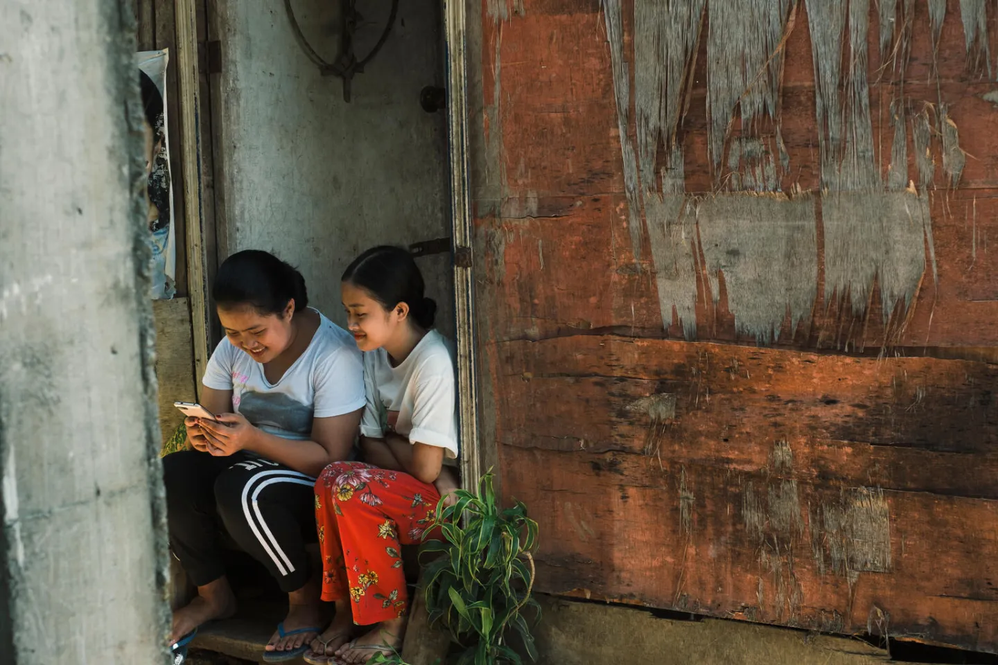 in Catbalogan, Philippines, Karylle (left), 14, and her little sister scroll through social media on the phone.
