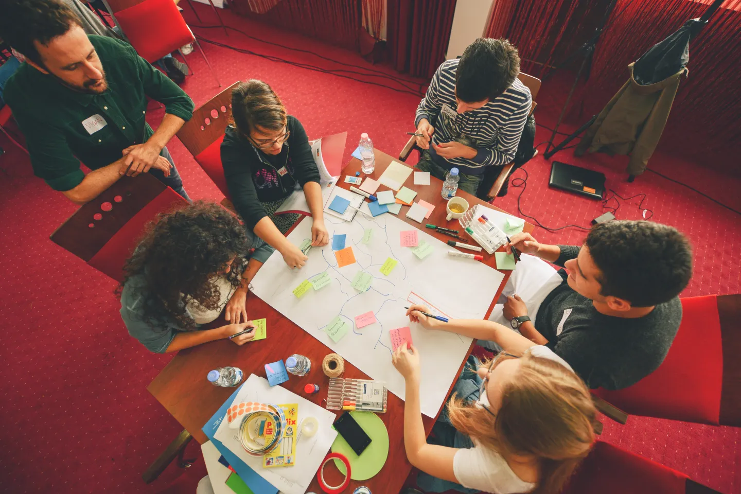 UNICEF staff, children, and youth in table putting their ideas on post its 