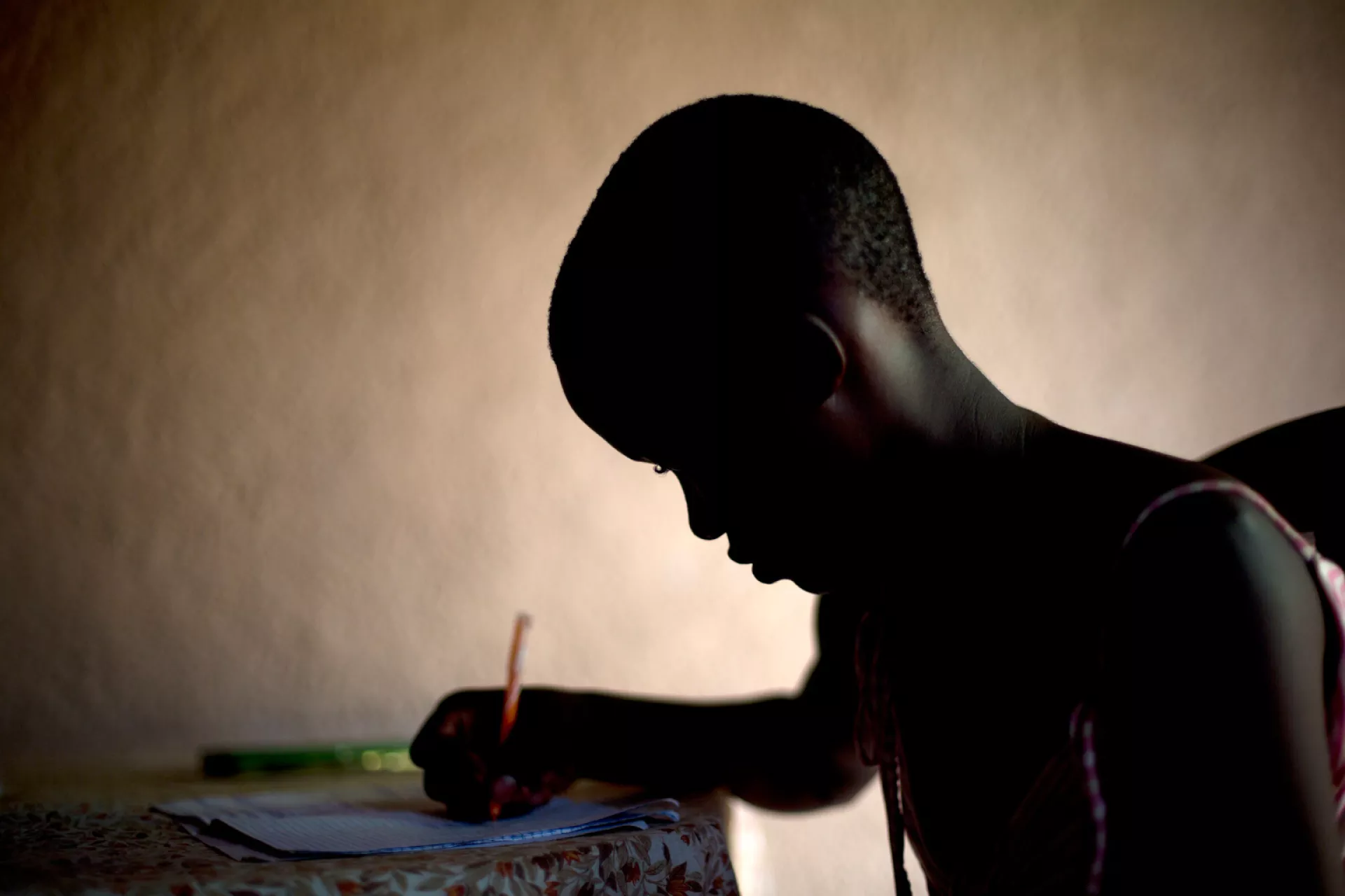 Gloria, 13 does school homework at their home in Musaga, in Bujumbura, Burundi
