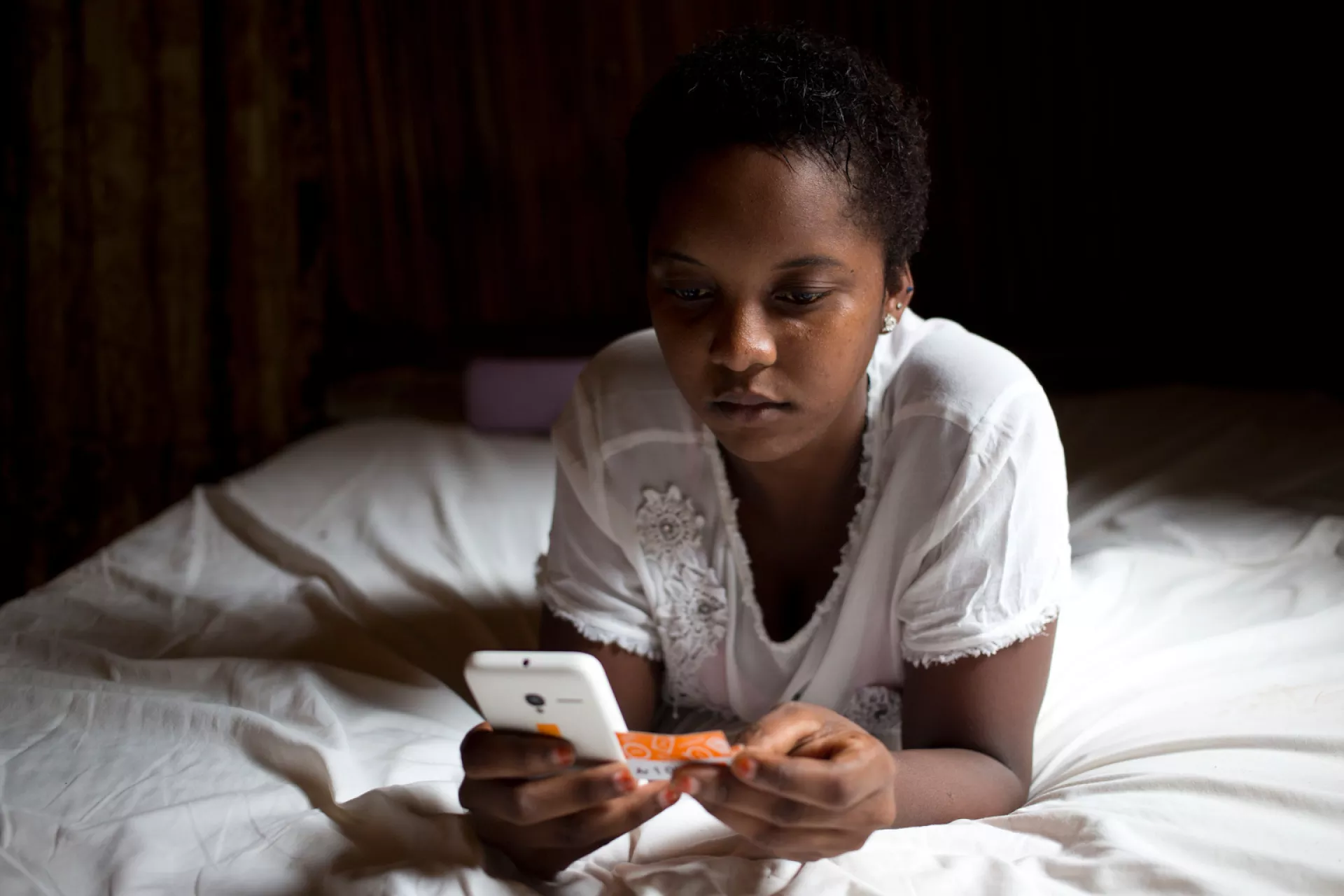16-year-old Charmela loads credit to her mobile phone, in her home on the island of Nosy Be, off the northwest coast of Madagascar.