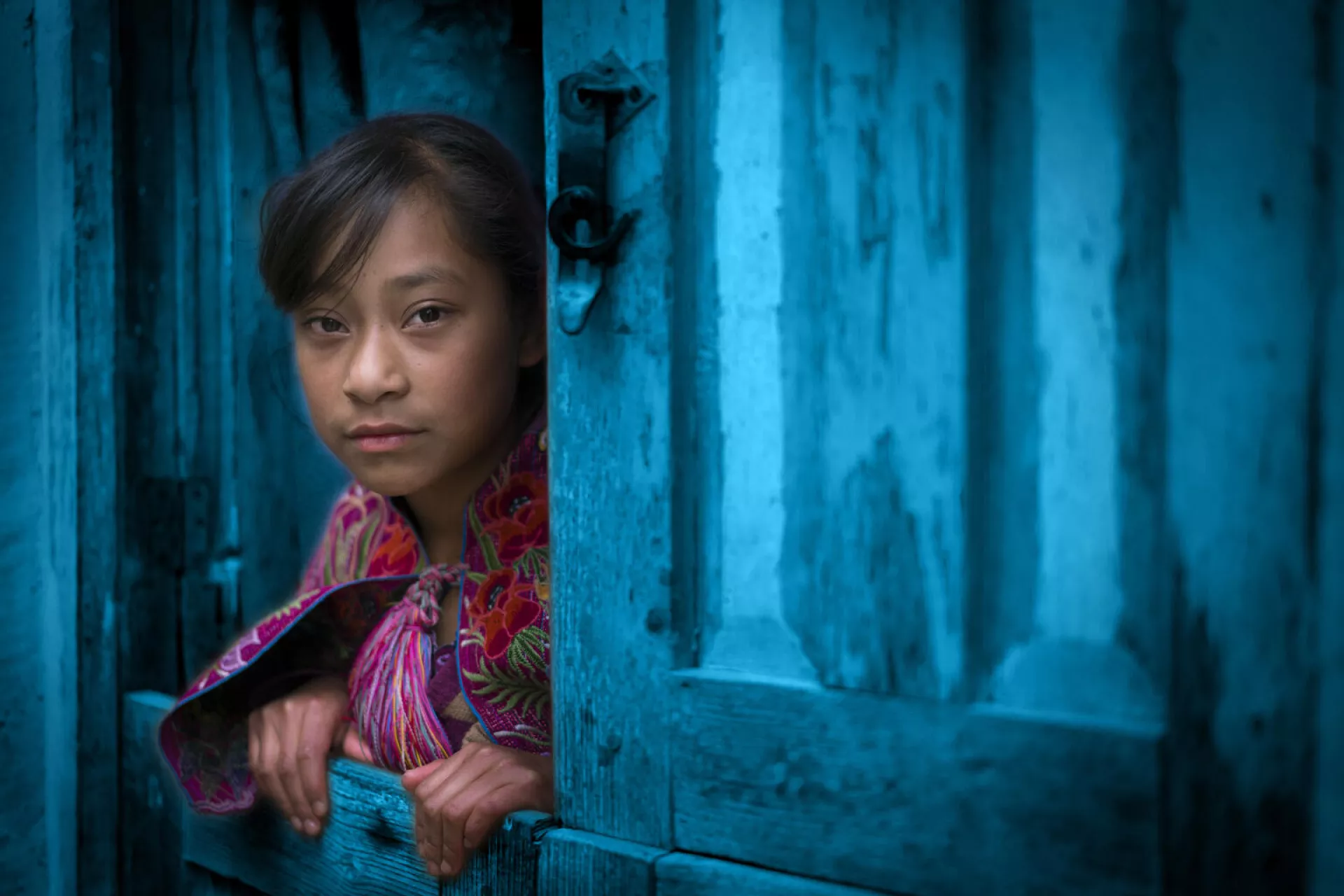 Lucia Maria Hernadez Perez an 11 years old living in Zinacantan Chiapas, Mexico, looks out from her home's split door with the bottom closed and the top part open. 