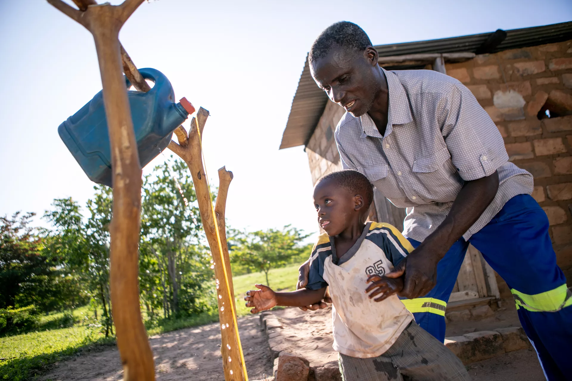 Man and child using tippy tap