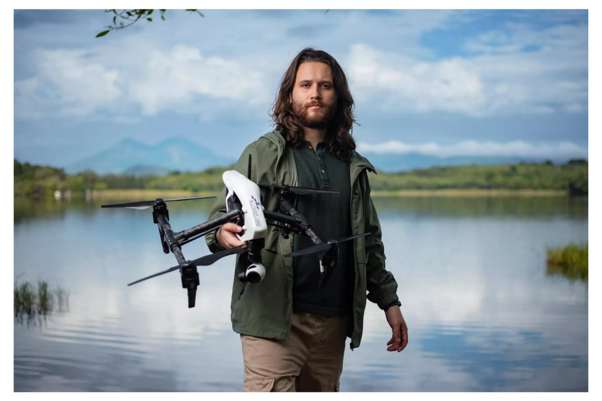 Dan Alvarez, drone engineer from the company Aerobots in Guatemala and team member of the UNICEF-led Dronebots project, stands holding a drone in front of the landscape at Laguna El Pino near Guatemala City, Guatemala