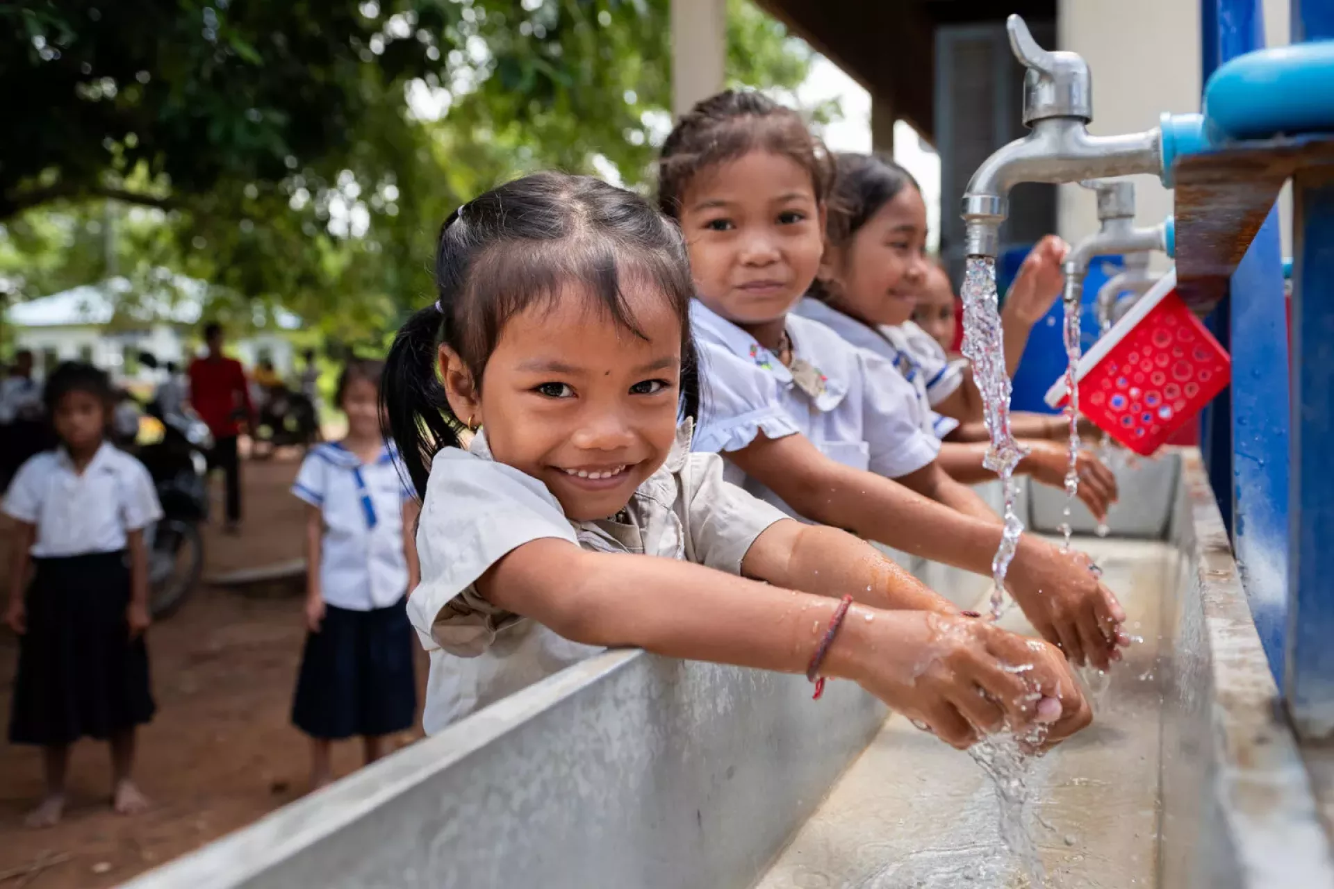 A school girl smiles as she washes her hands