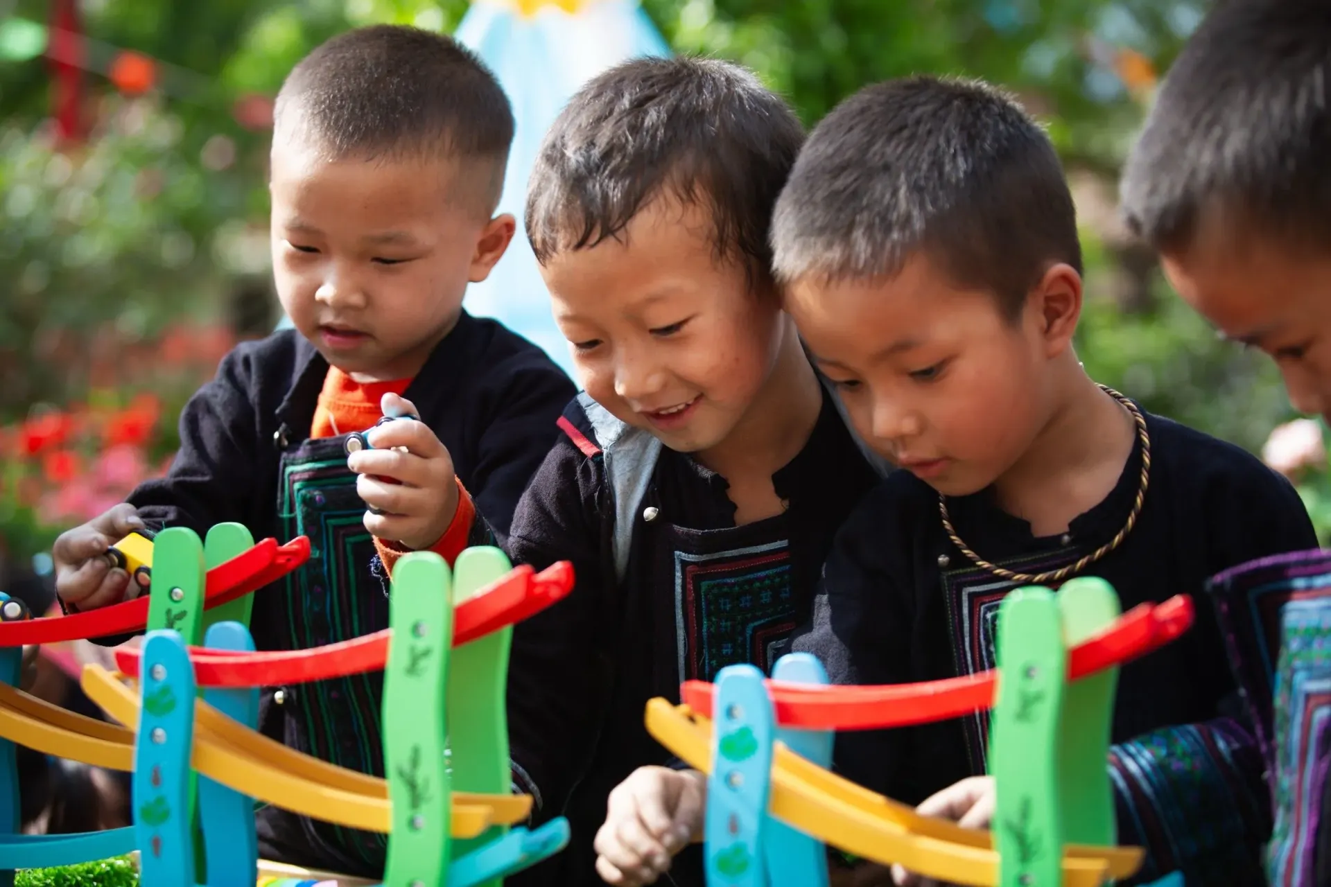 Three young boys play with colourful wooden toy cars at a preschool in Viet Nam.