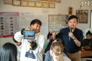 boy showing something to a classroom on a tablet