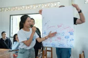 student showing something on a poster in classroom