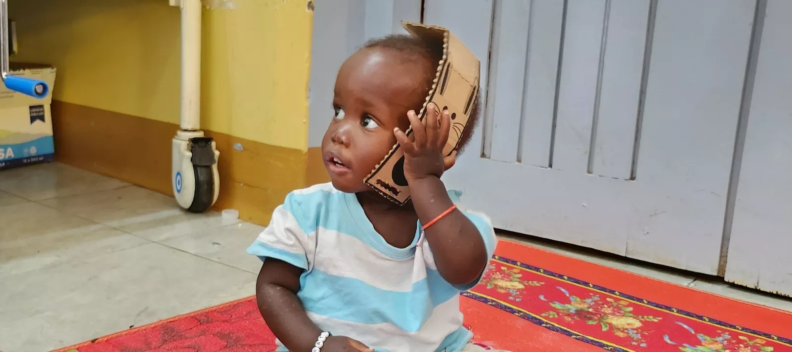 Child playing with toys made from RUTF carboard packaging in health center in Uganda