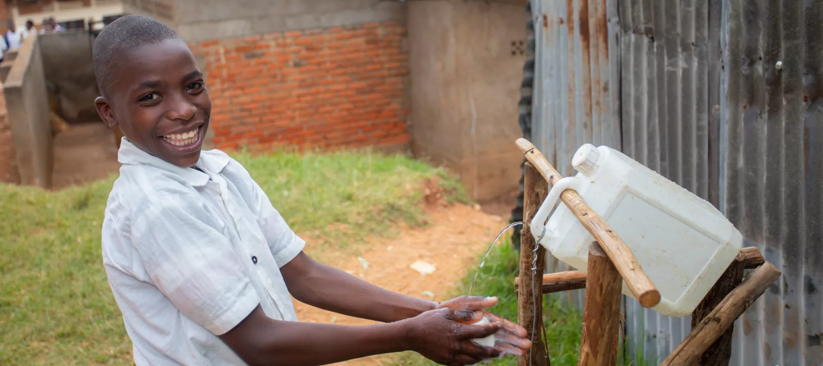 German, 15 and a student in Senior 1 at Groupe Scolaire Rususa, pauses to wash his hands using a tippy-tap before heading to the refectory for lunch.