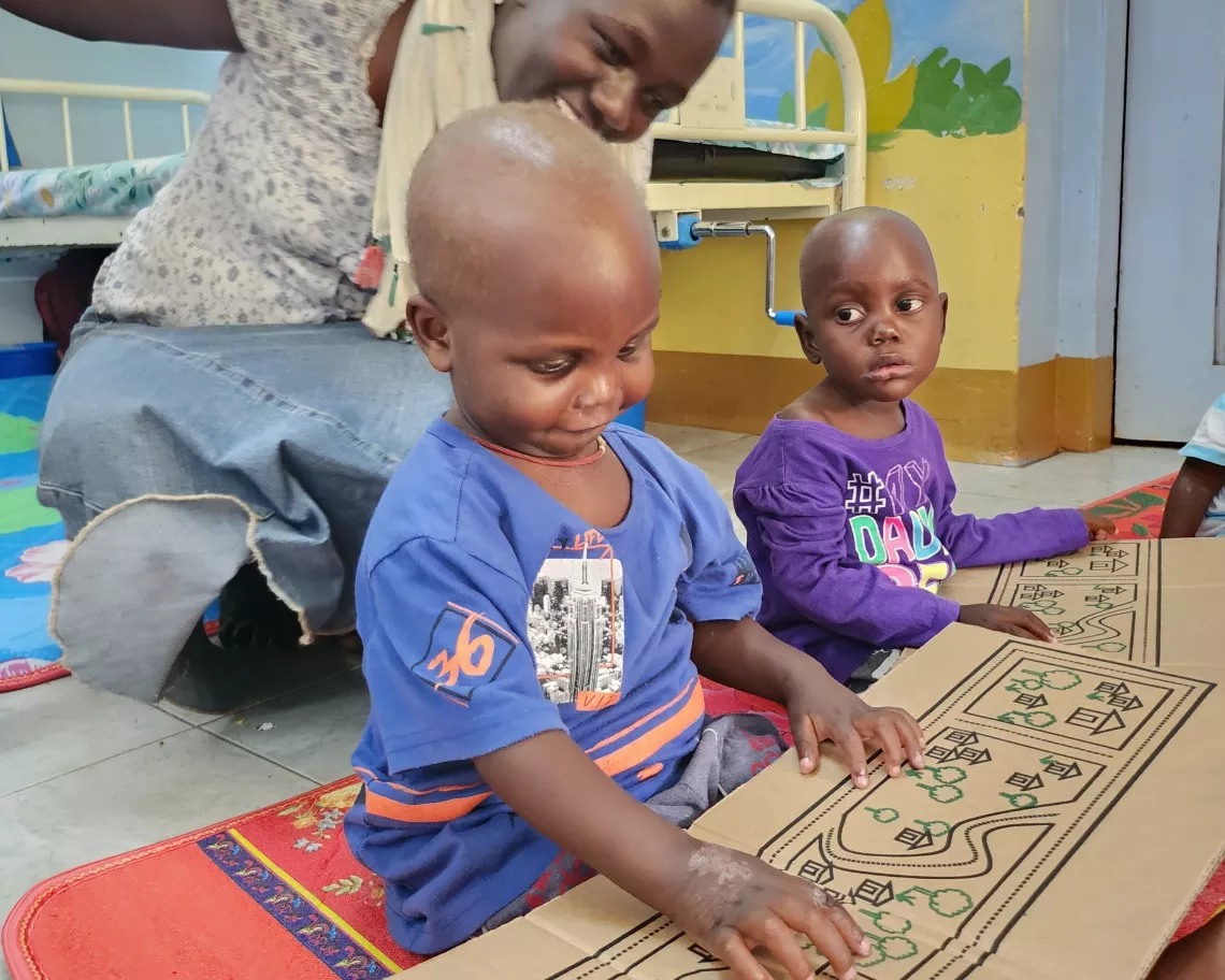 Child playing with toys made from RUTF carboard packaging in health center in Uganda