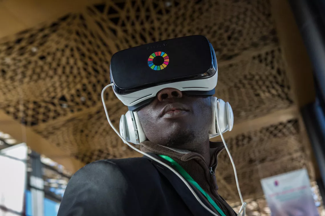 Journalist Babacar Fall, wearing a headset, watches a virtual reality video at the UNICEF exhibition at the Global Partnership for Education (GPE) Financing Conference in Diamniadio, Senegal