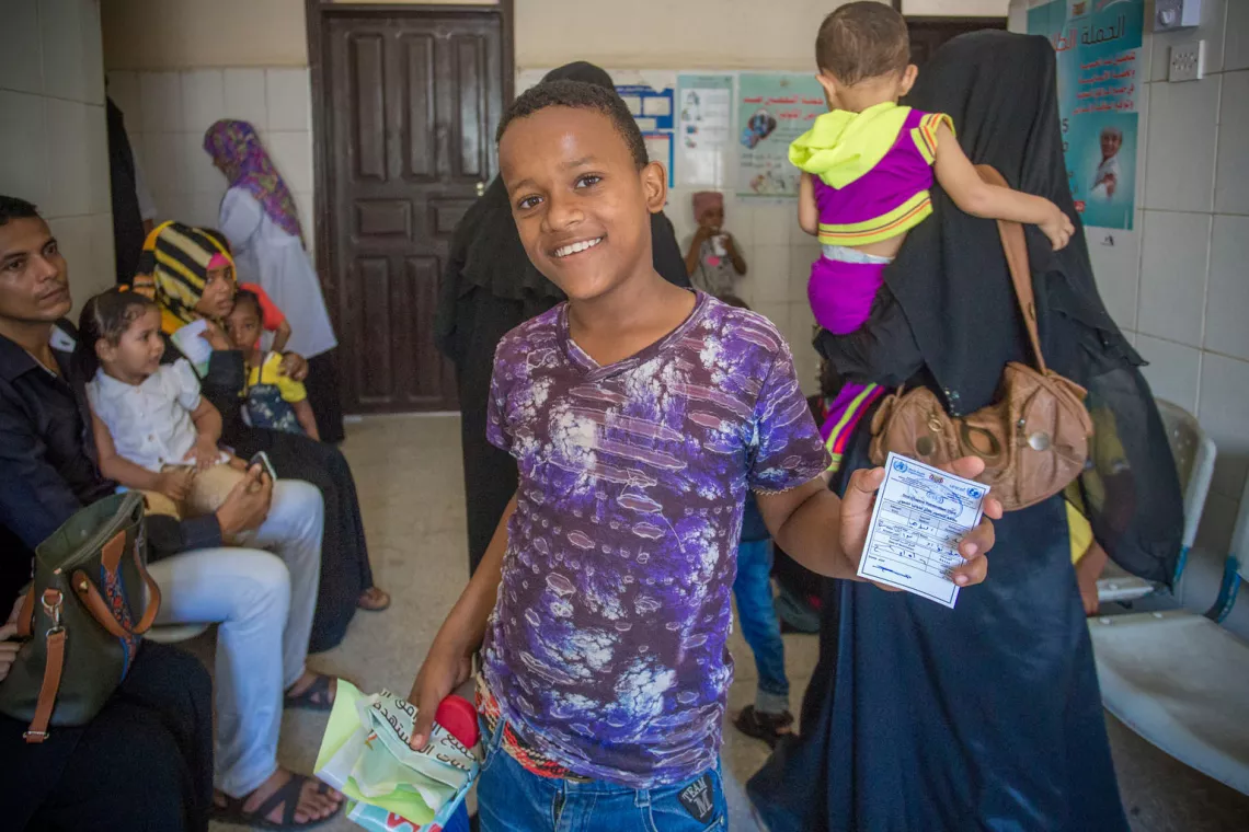 In Aden, Yemen, a boy holds up his vaccination card.