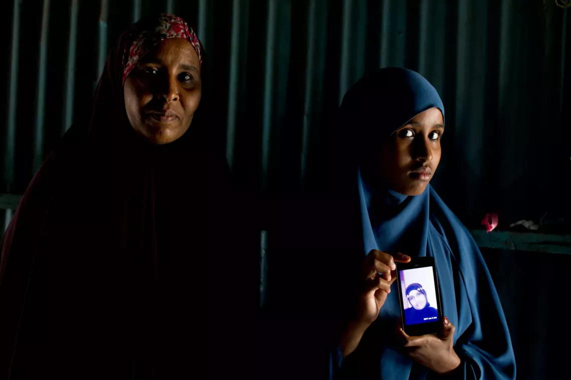 Girl in Somalia holds her phone up.