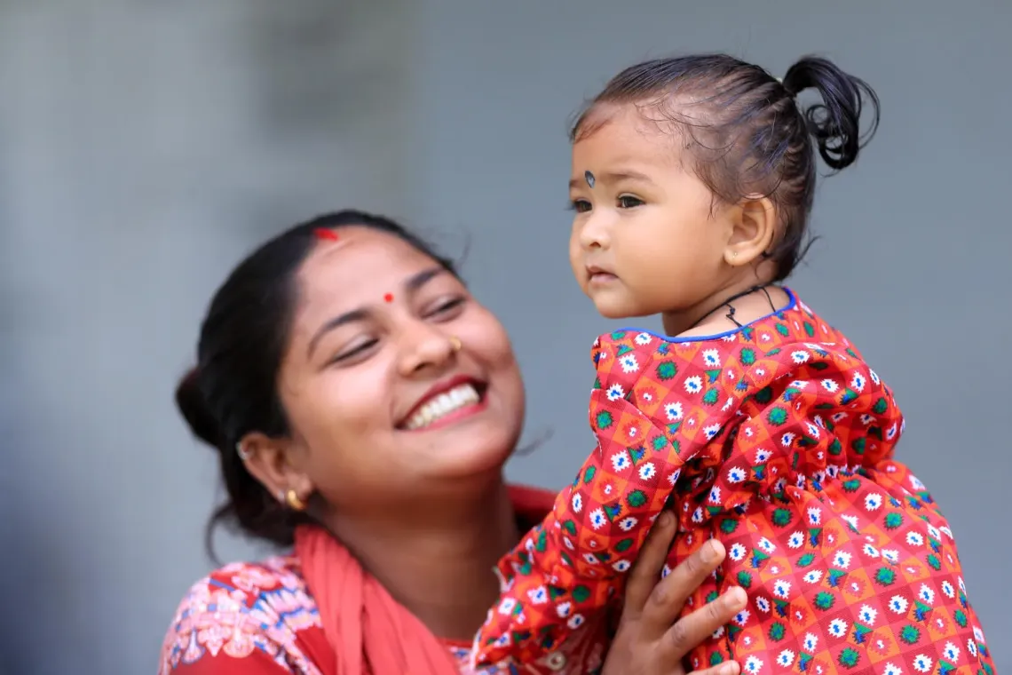 A woman plays with her one-year-old daughter