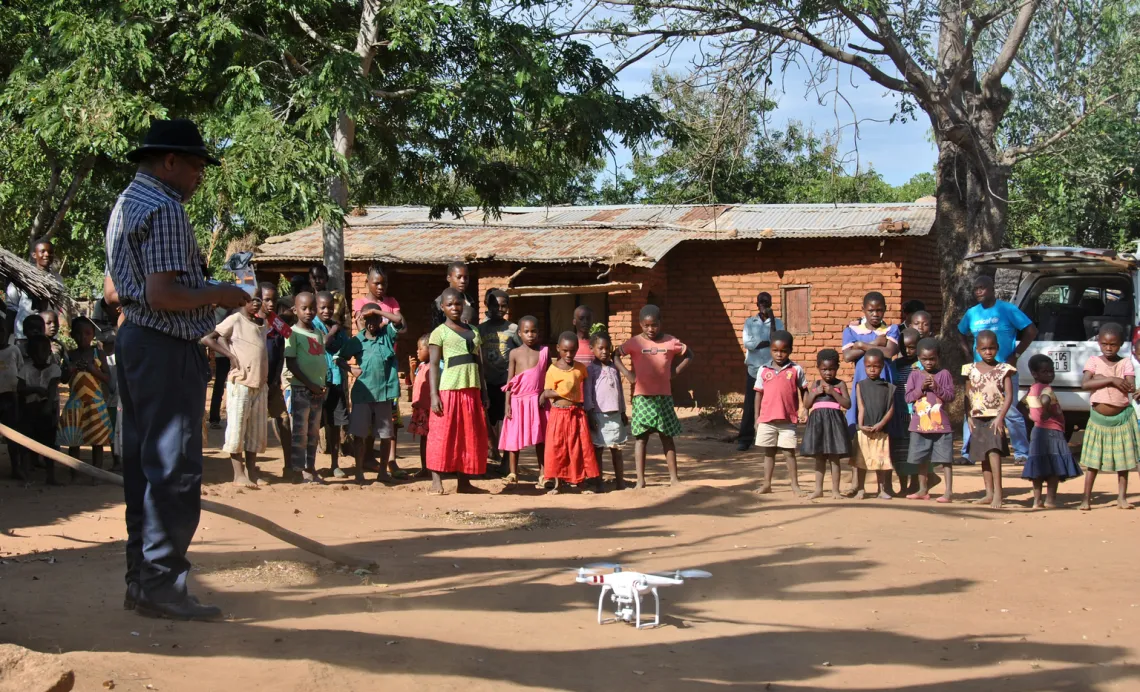Chief Air Traffic Controller Steve Mkandawire (left), one of five Civil Aviation certified pilots, demonstrates a drone to residents in Thipa vllage, Kasungu District, Malawi