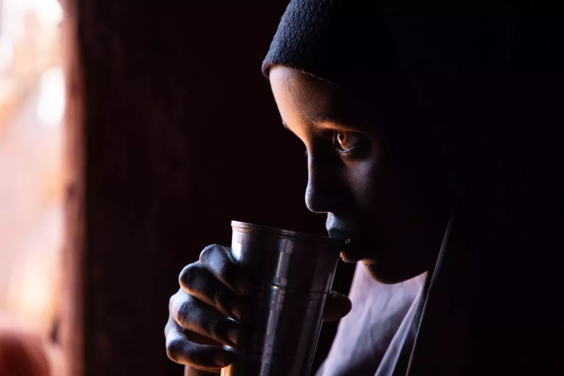 A girl drinks water from a metal cup 