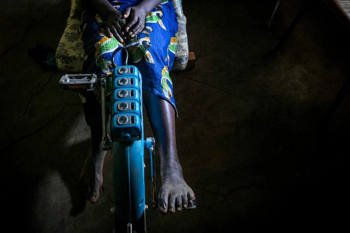 A woman in Gitega province charges LED lamps using a pedal-powered generator.