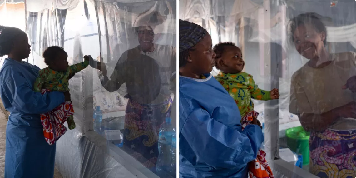 A baby reaches out to touch his mother&rsquo;s hand through a plastic sheet in an Ebola Treatment Centre 