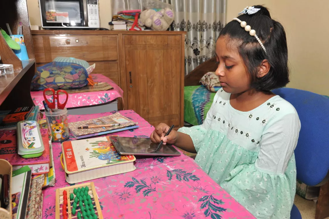 Mounee Mahdeya, 10, uses her computer tablet to complete schoolwork for her Level IV class at Monipur High School and College in the Mirpur area of Dhaka, capital of Bangladesh.