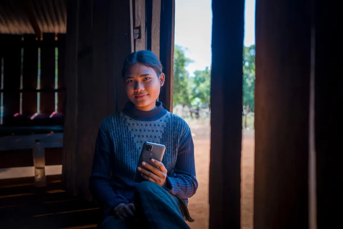 Cambodian girl looking at the camera while holding her phone. 