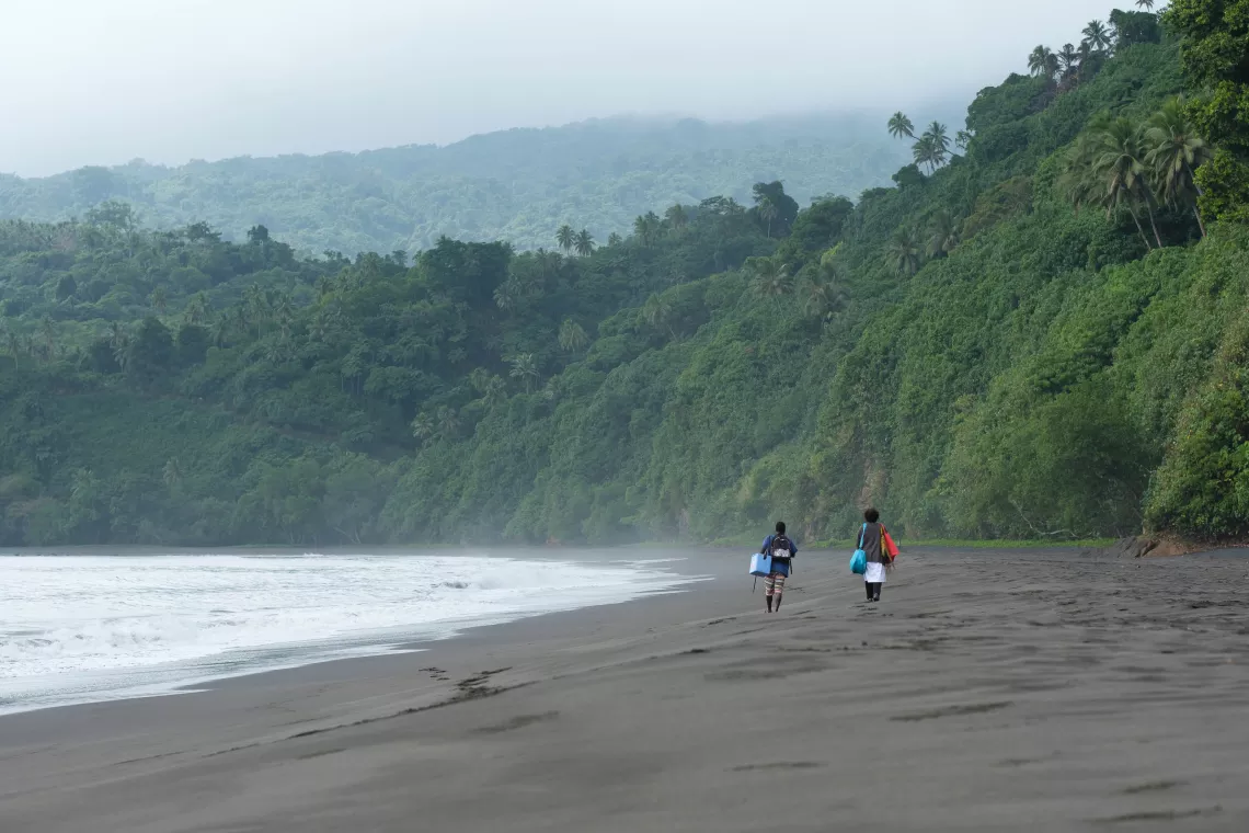 Midwife Roslinda Narwayen, Vaimali Health Centre, Epi Island. Roslinda and her assistant on a 3 hour hike down the coastline to deliver vaccines for an MCH clinic at Ngala village. Because there are no fridges store vaccines, the vaccines must be administered immediatey at journeys end. She spent three dyas trying to contact the nurse at the distant health centre but because of limited communication network, she decided to just go. 