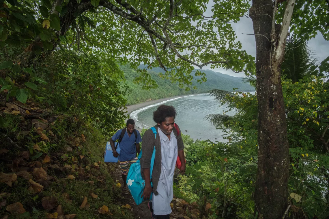 Midwife Roslinda Narwayen, Vaimali Health Centre, Epi Island. Roslinda and her assistant on a 3 hour hike down the coastline to deliver vaccines for an MCH clinic at Ngala village. Because there are no fridges store vaccines, the vaccines must be administered immediatey at journeys end. She spent three dyas trying to contact the nurse at the distant health centre but because of limited communication network, she decided to just go. 