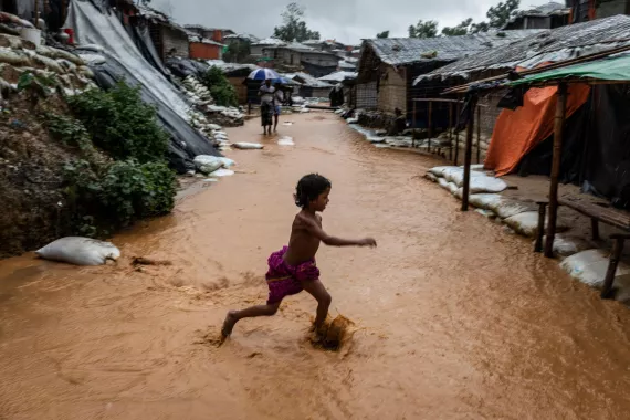 A child runs through muddy water in a refugee camp