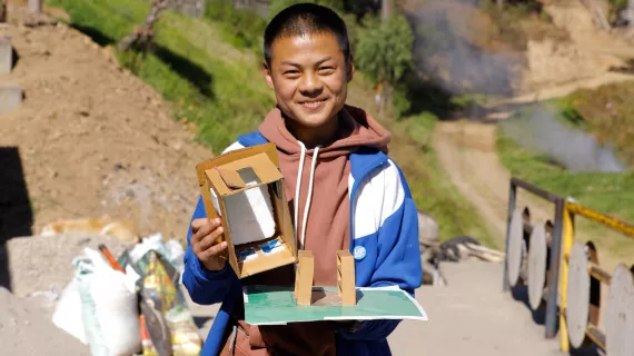 A student of Gaselo Central School in Wangdue district in western Bhutan holds a prototype of their UPSHIFT project, a cold storage to store the school’s vegetables and food supplies.