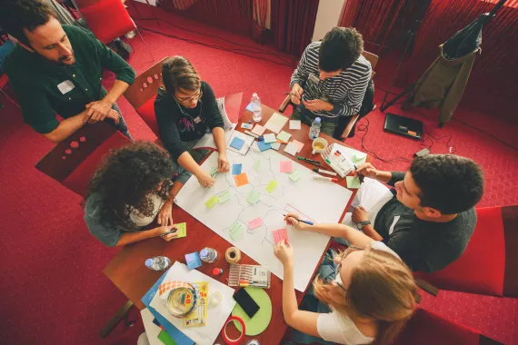 UNICEF staff, children, and youth in table putting their ideas on post its 