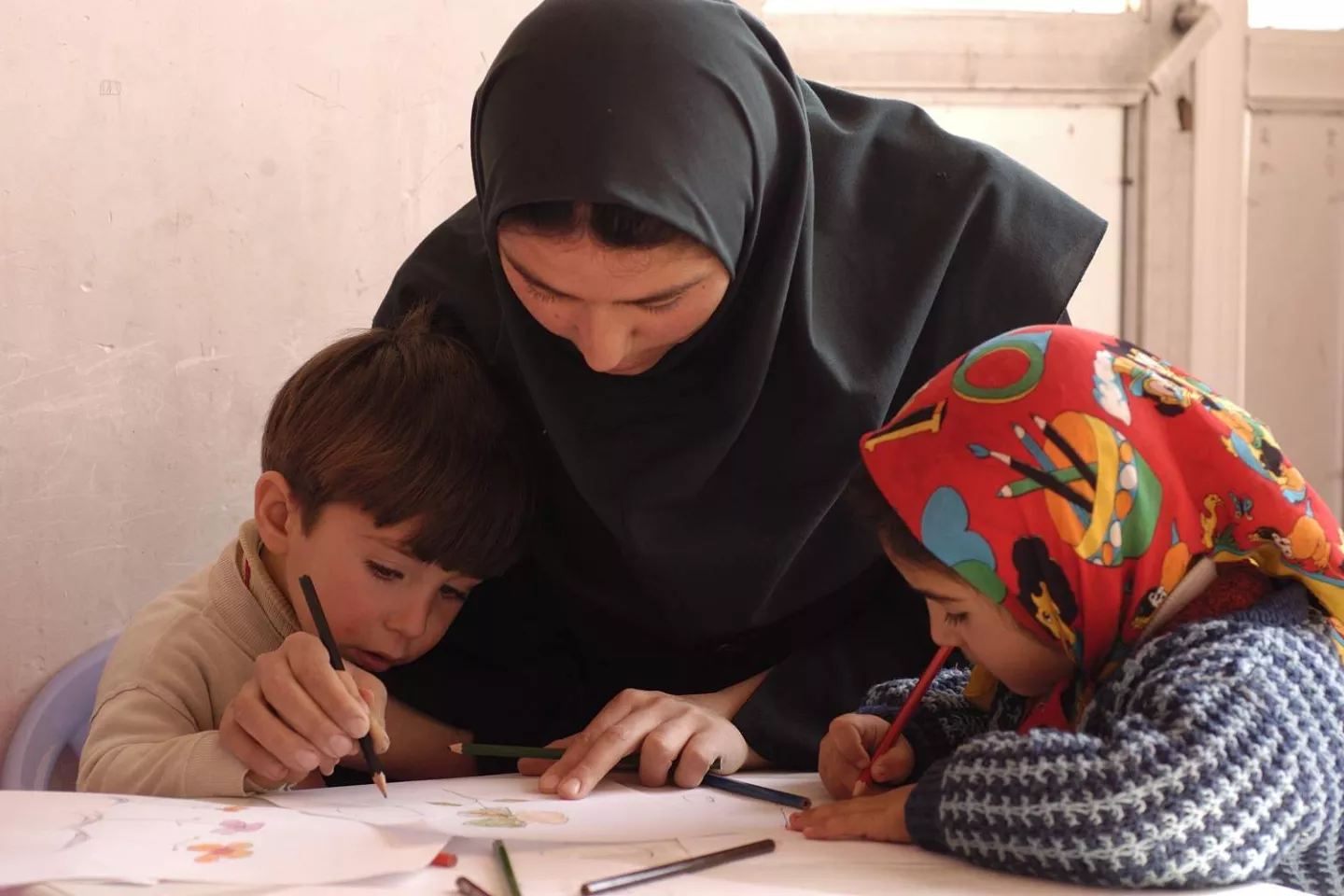 A teacher helps a child to write 