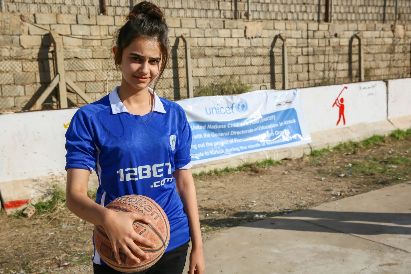 Nabaa, 17, holds a basketball before a game at Al-Yaqatha High School in Kirkuk's Arafa District.   "I love playing basketball," she says. "I am following in my father's footsteps. He was also a basketball player."