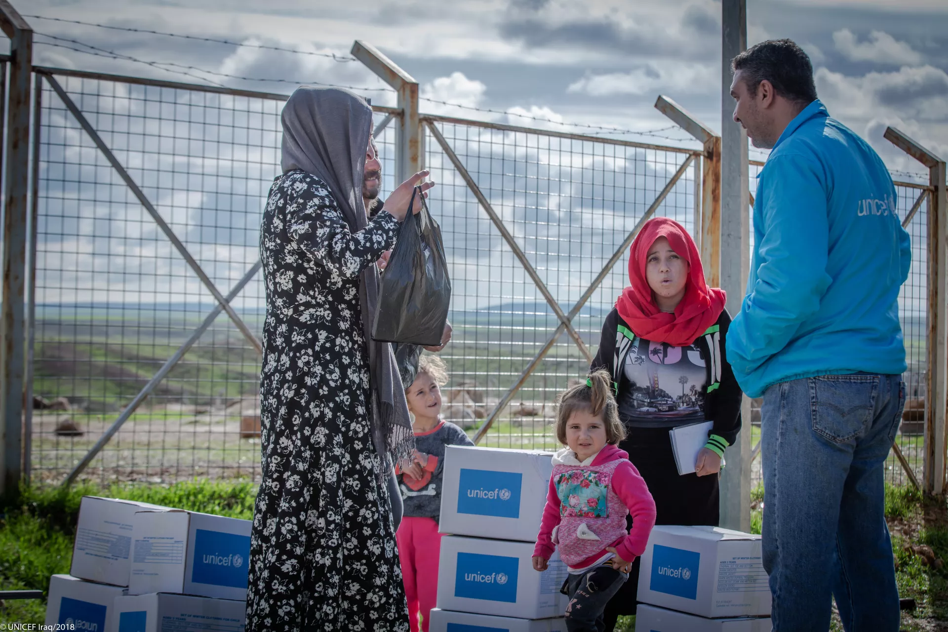 A UNICEF staff member speaks to a mother and her children, after they received winter clothes support.