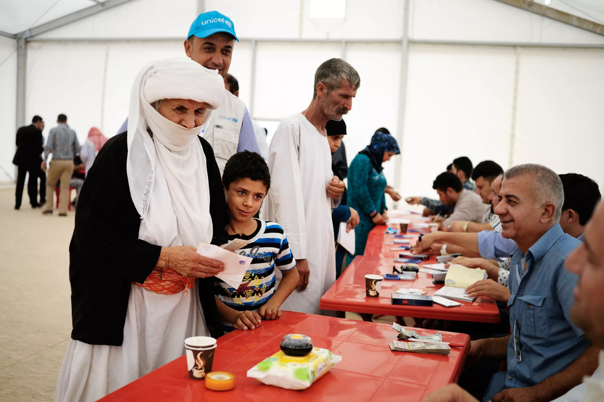 Shirin, 72, with her grandson Rian, 8, receive cash assistance during a UNICEF facilitated distribution in Bajet Kandala IDP Camp in Dohuk Governorate. 