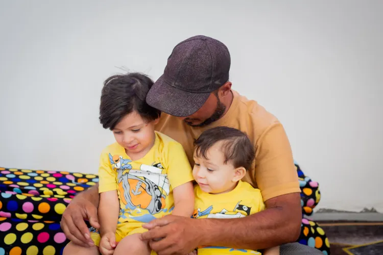 A father holds his two children, sitting close together.