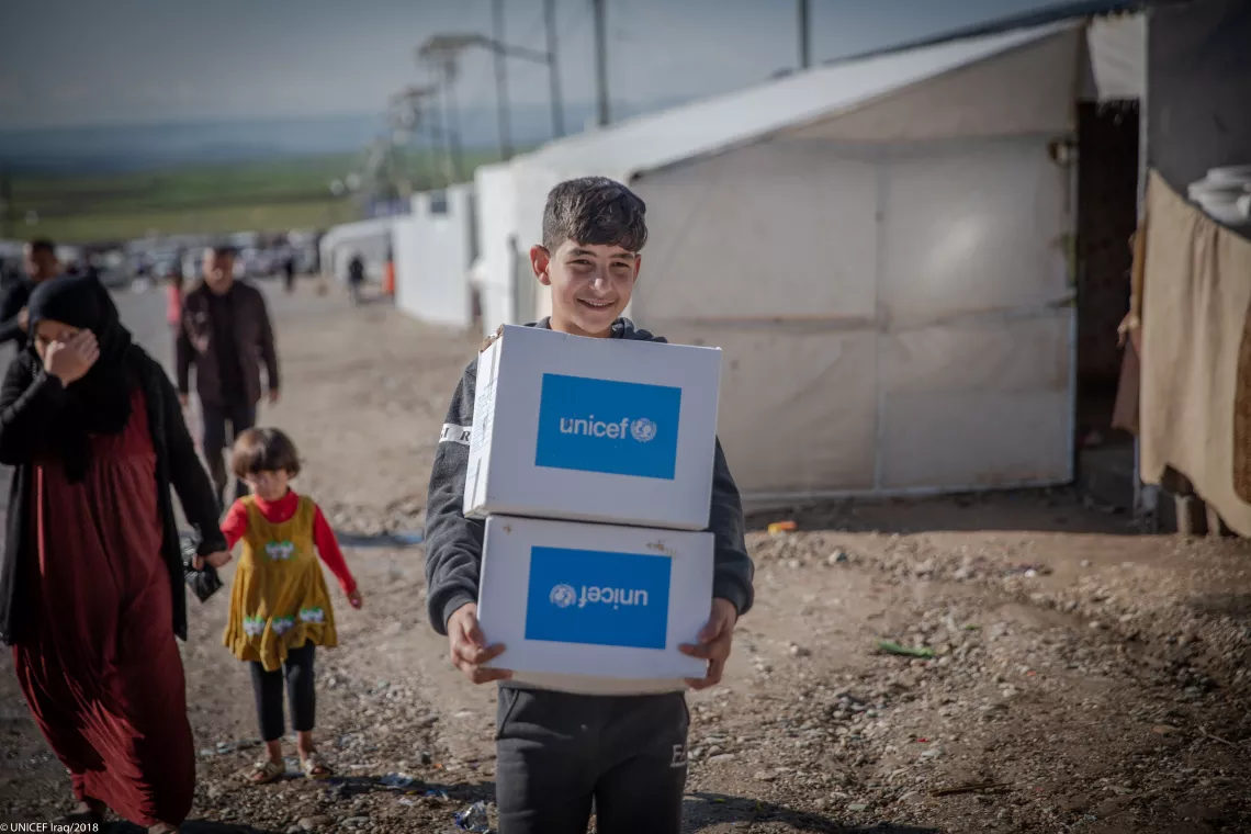 A boy carries boxes of winter clothes supplied by UNICEF in Northern Iraq