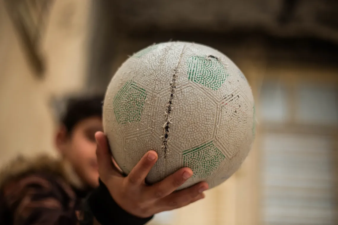 Adam plays football during a UNICEF-supported activity that helps children rebuild confidence and social connections.