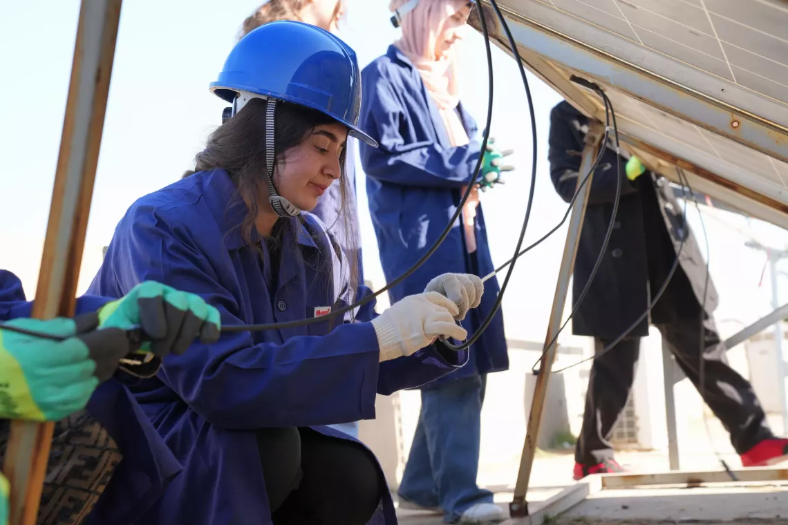 Lava Salih connects wires to power up a solar system in Erbil Governorate, Iraq.   