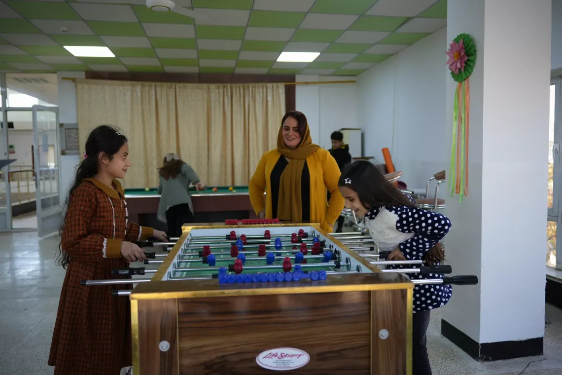 Begard watches with a smile as her daughters play at the Child Protection Center in Chamchamal District, Sulaymaniyah Governorate, Iraq, feeling happy and proud.