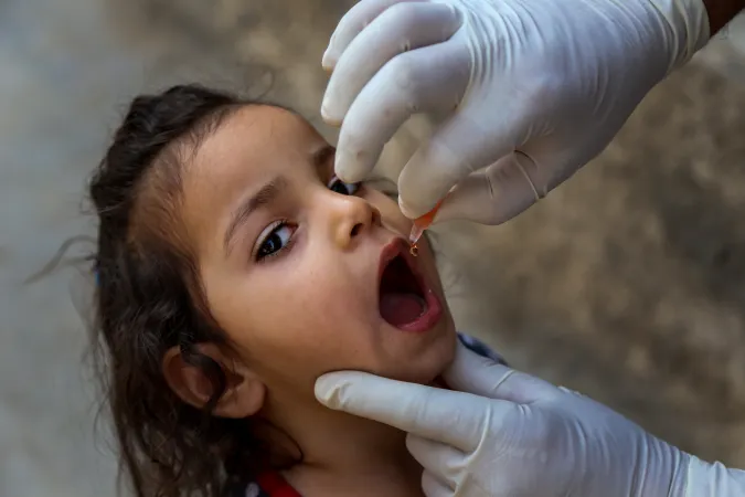 health workers give 4 year old Zaenab from Sadr city, a neighborhood in Baghdad, Iraq, two drops of oral polio vaccine as part of a five-day polio vaccination campaign aimed at reaching 5.8 million children in Iraq.