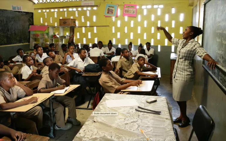 Photograph of a teacher leading a class discussion in a classroom at Drew Avenue Primary School in Kingston. UNICEF provided the school with textbooks and other supplies