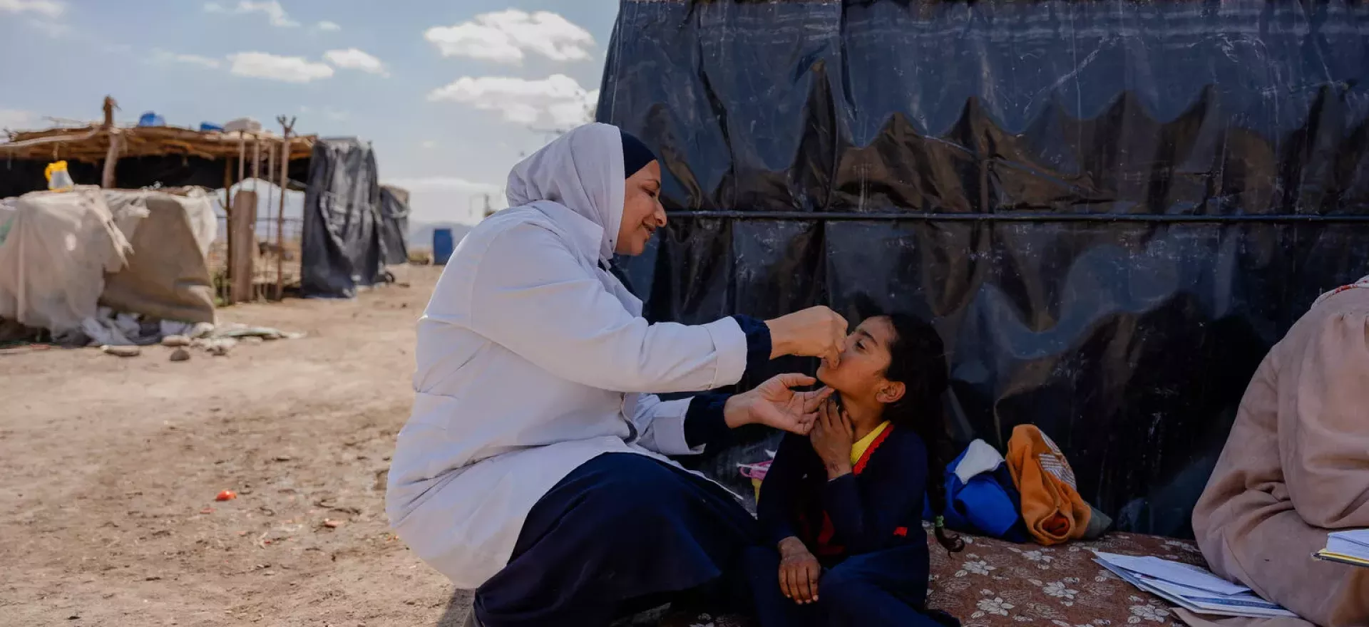 A health worker vaccinating a child in a remote area.
