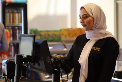 A woman standing behind a cash register in a supermarket. 